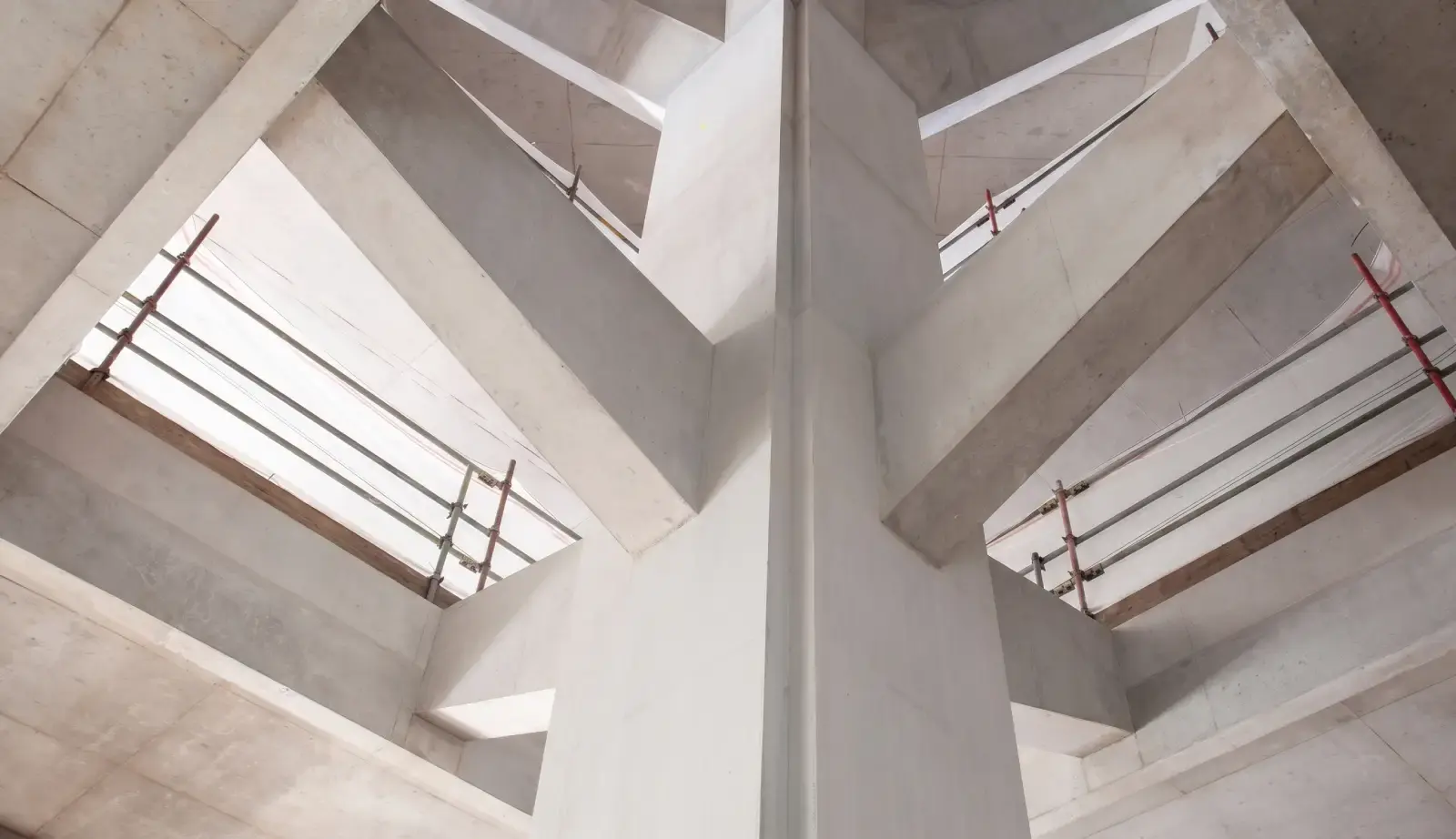 Looking up through cast in-situ reinforced concrete cores and slab edges mid-construction, with backpropping supporting the floors above